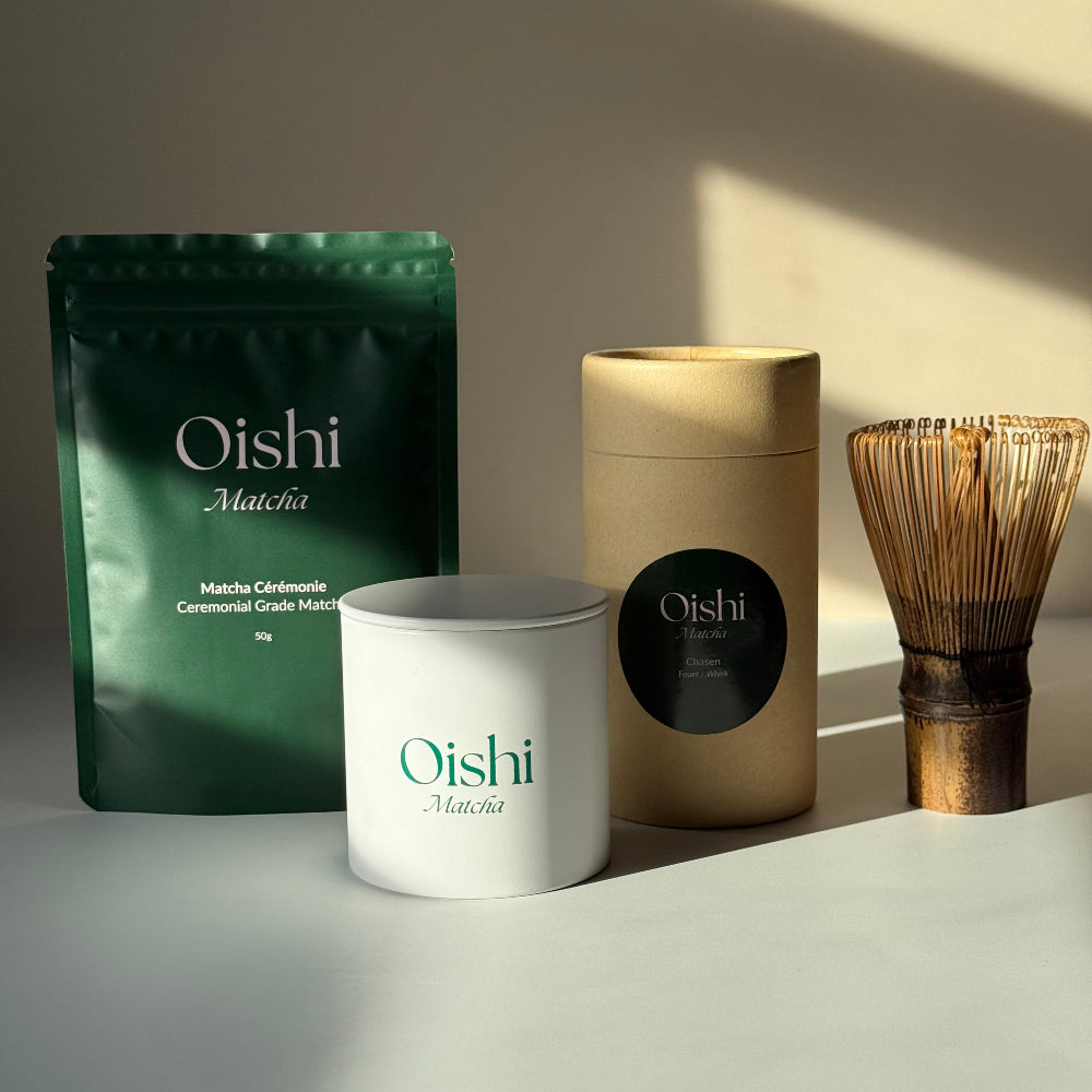 Ensemble comprenant le sachet Oishi Matcha de 50g, une boîte de stockage blanche avec logo vert, et un fouet