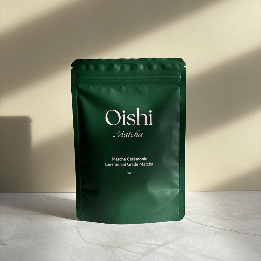 Sachet de thé matcha Oishi Matcha, face avant, sur support en marbre et fond beige.